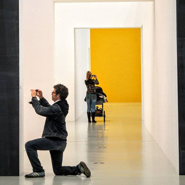 Student holing a camera while another student holds a camera in the background