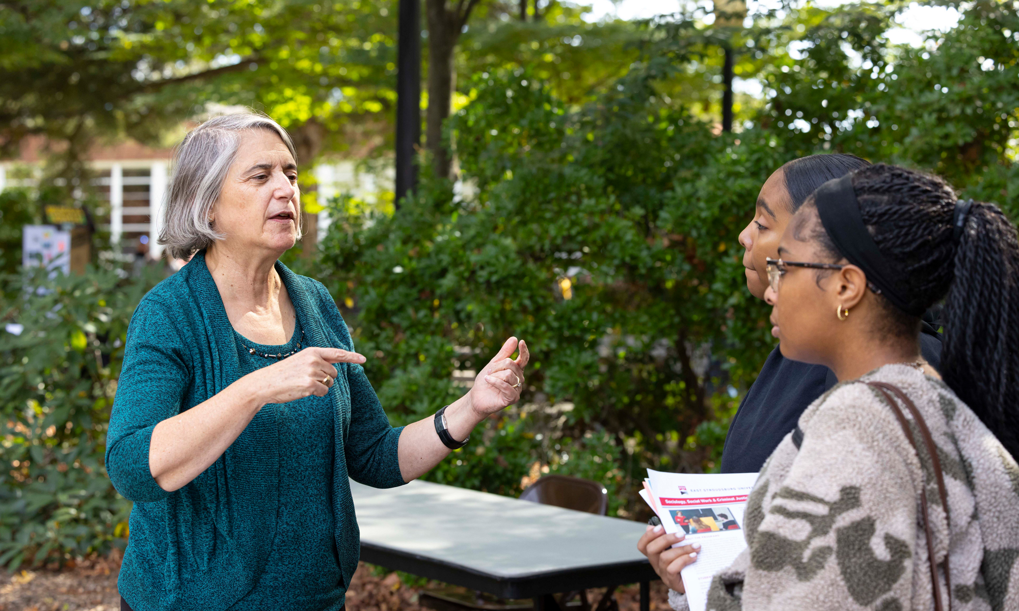 Faculty member talking with students in front of Stroud Hall