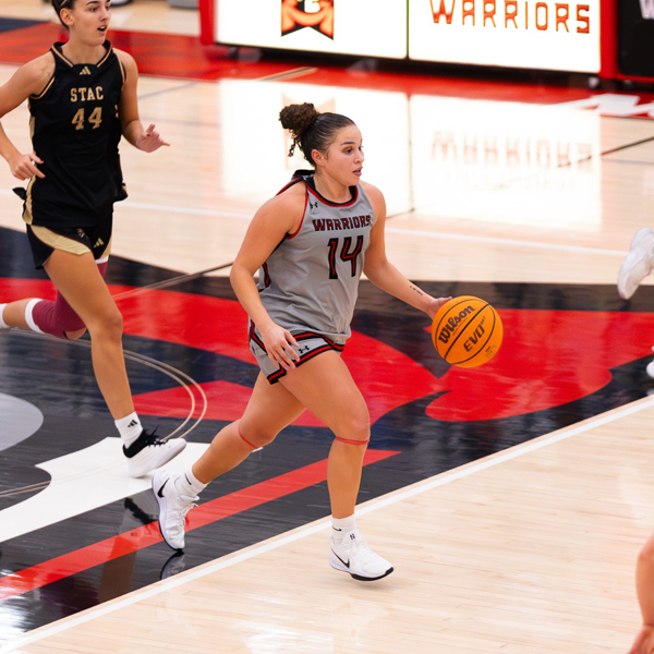 Female basketball player dribbling down the court
